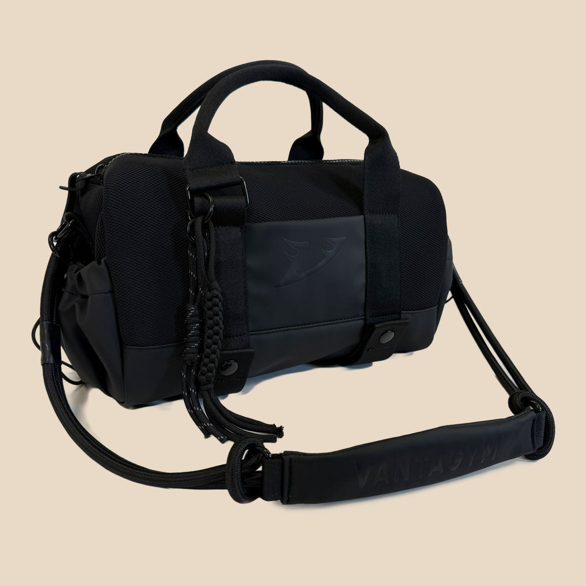Vantagym Orion black mini duffel bag with dual top handles, a detachable shoulder strap, and a braided tassel detail